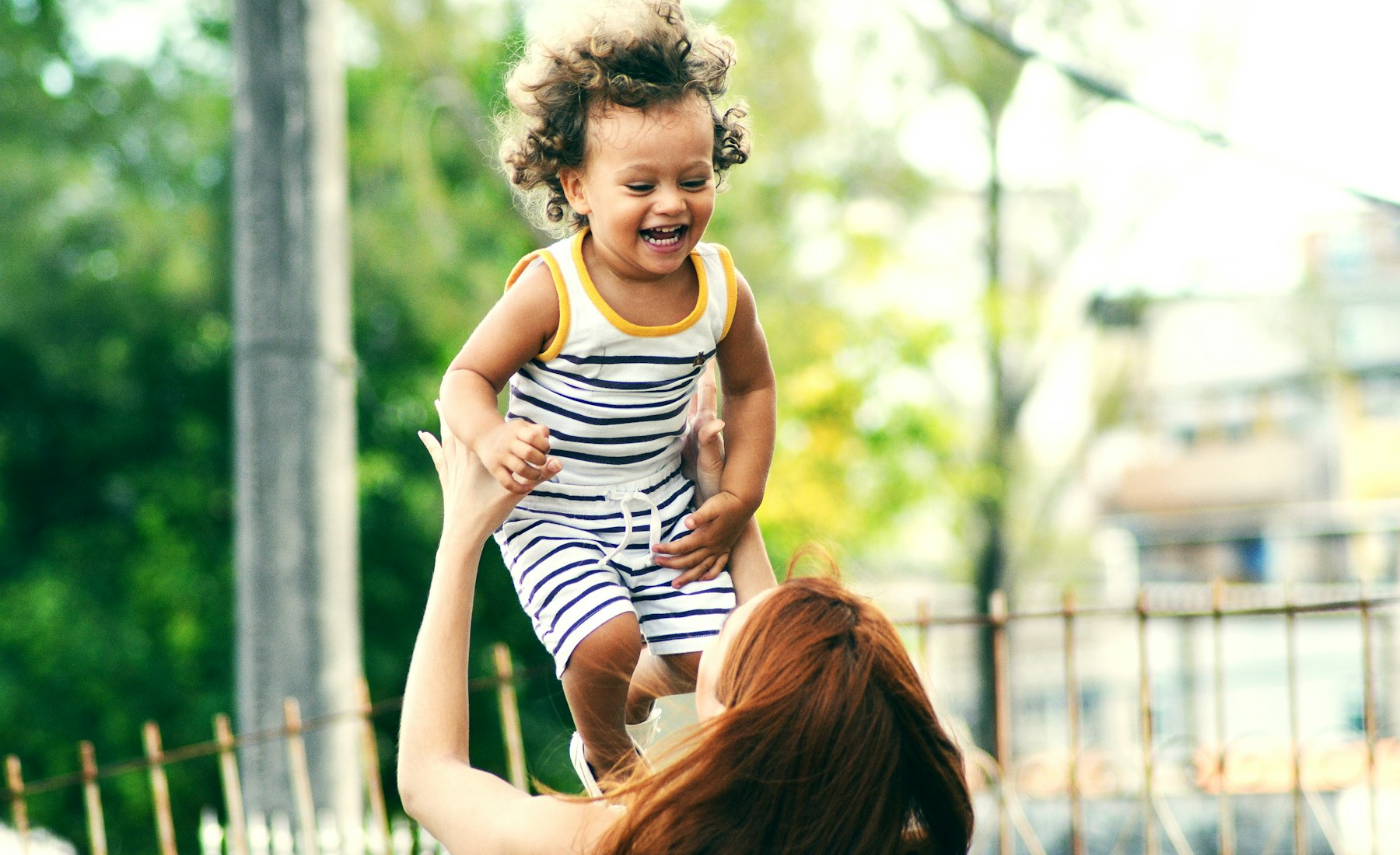 A parent lifting their laughing child into the air